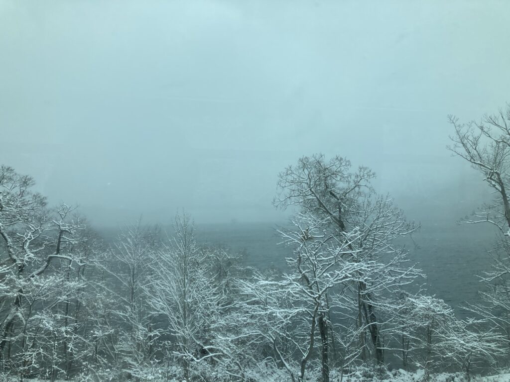 バスの窓から見た、雪の木々と十和田湖