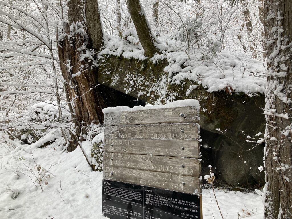 雪の中の石ヶ戸の看板と大きな岩