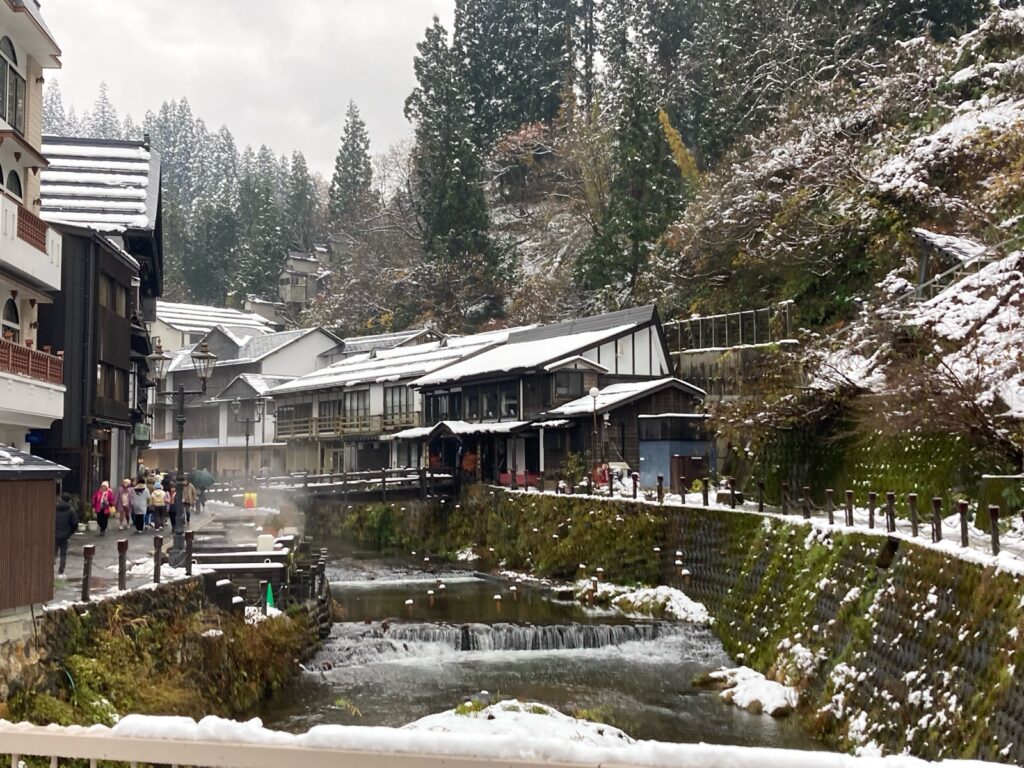 屋根に雪がのった銀山温泉の旅館と銀山川