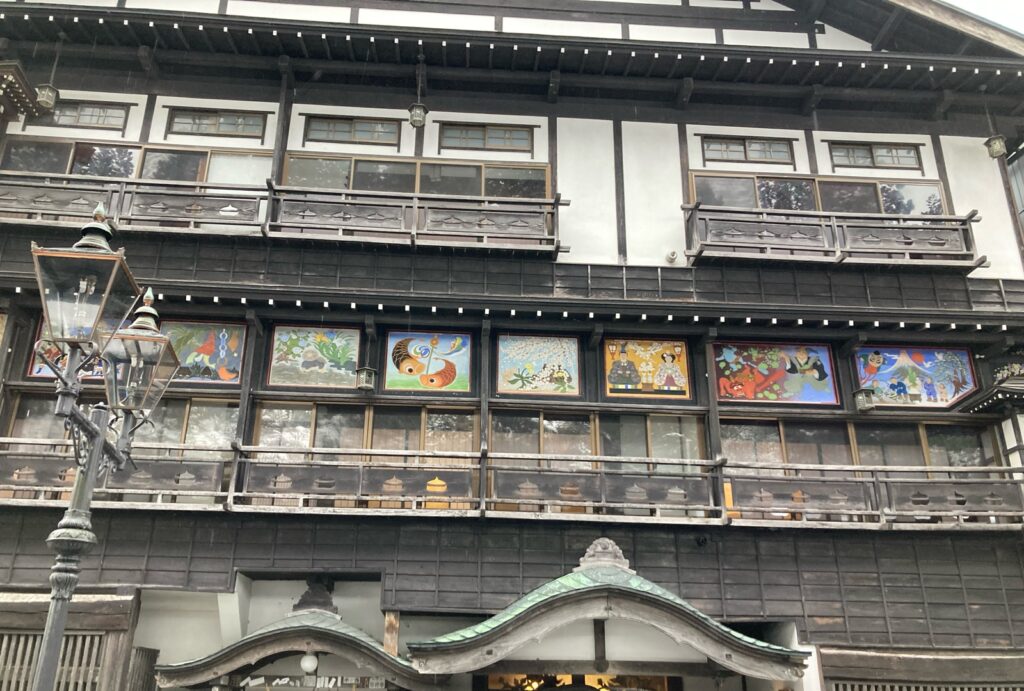季節の絵が並ぶ銀山温泉の旅館の壁とガス灯