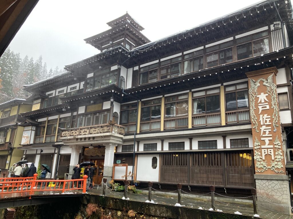 「木戸佐左エ門」と書かれた柱のある木造の旅館と赤い橋
