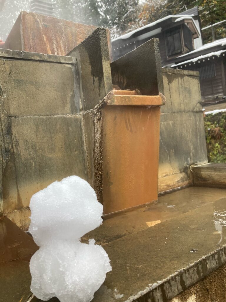 銀山温泉の足湯の湯口と小さな雪だるま